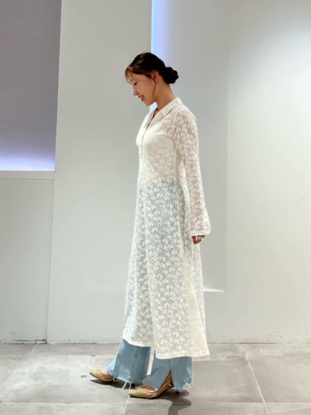 ホワイト系のシャツワンピース、ホワイト系のキャミソール、ブルー系のデニムパンツを着用したレディースの春コーディネートの2枚目の写真