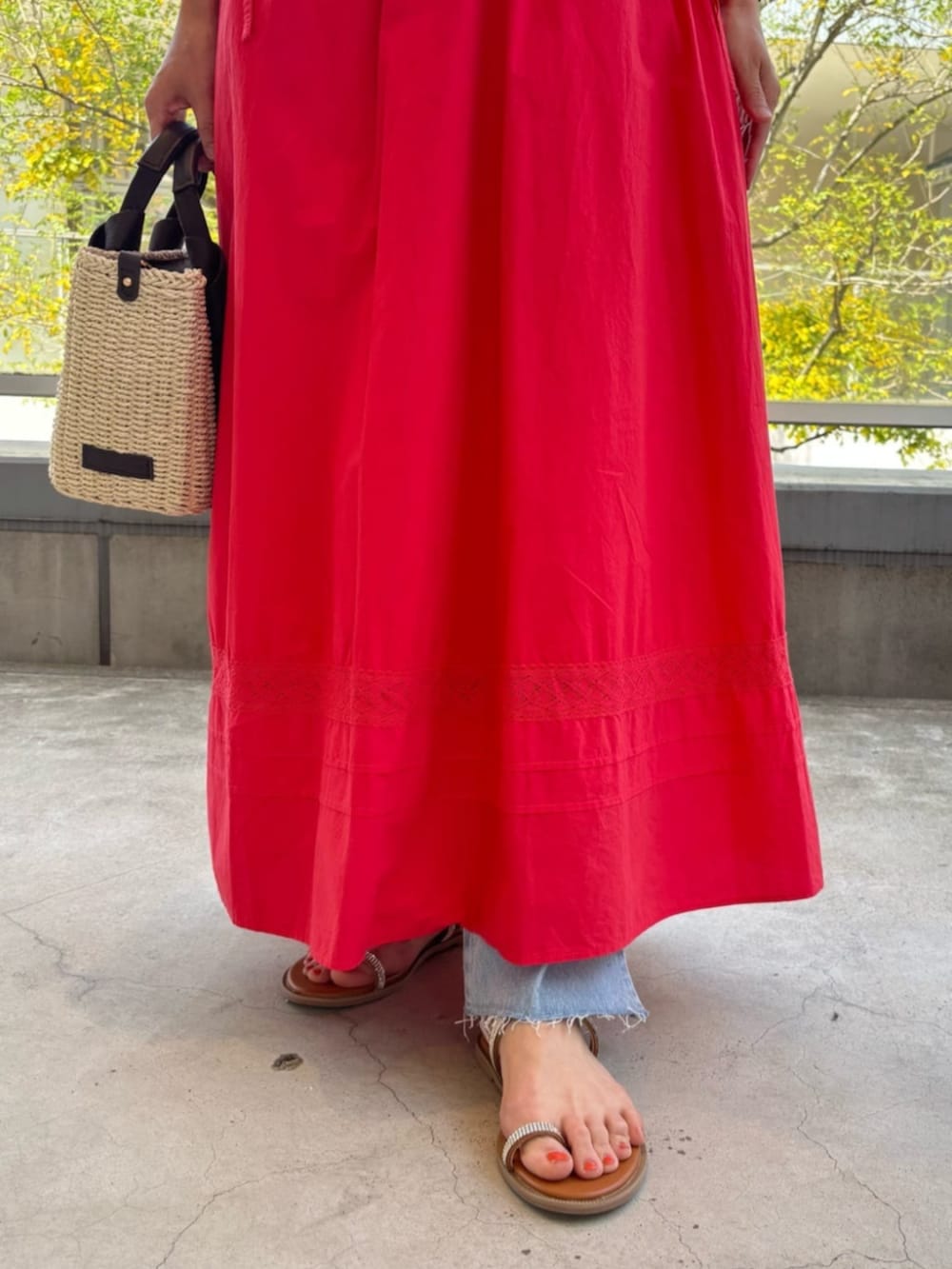 ブルー系のデニムパンツ、レッド系のワンピースを着用したレディースの春コーディネートの5枚目の写真