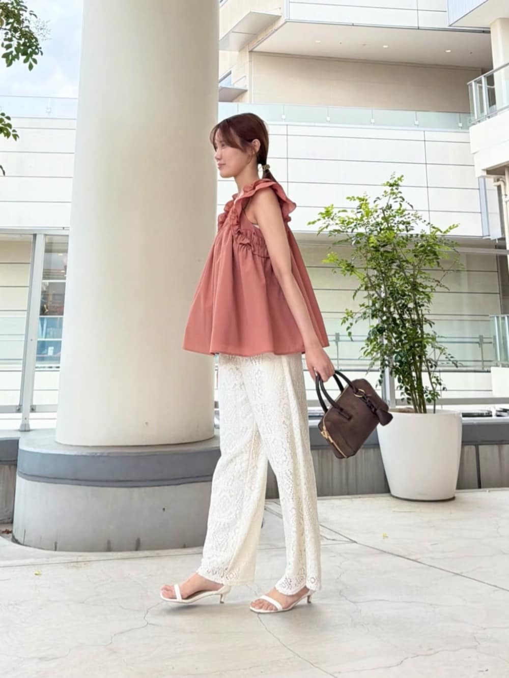 ブラウン系のボストンバッグ、ホワイト系のその他パンツ、オレンジ系のシャツ/ブラウスを着用したレディースの夏コーディネートの3枚目の写真