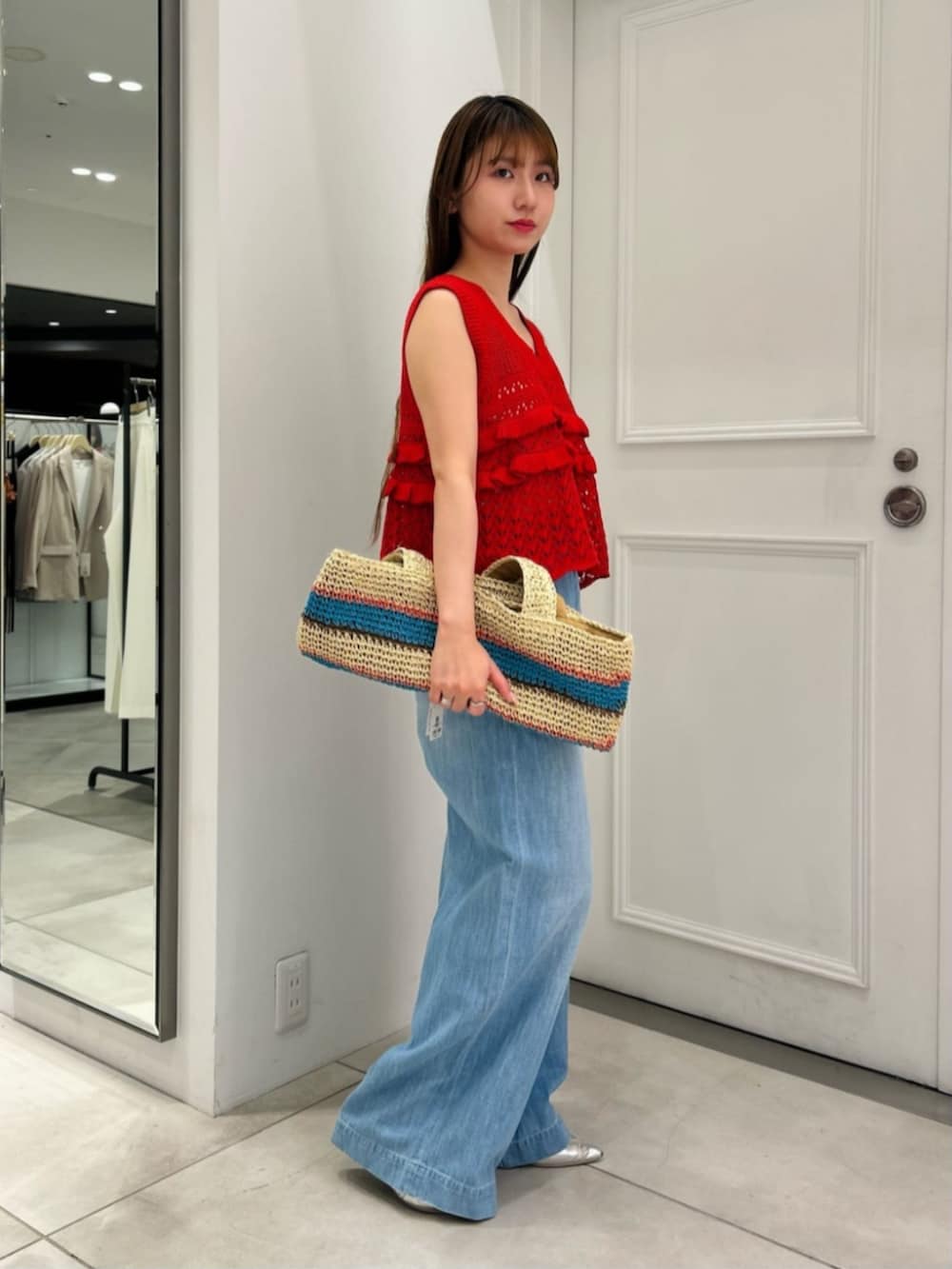 ブルー系のトートバッグ、レッド系のニット/セーター、ブルー系のデニムパンツを着用したレディースの春コーディネートの3枚目の写真