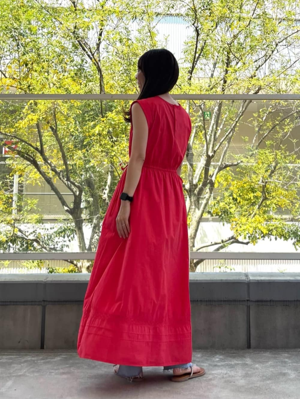 ブルー系のデニムパンツ、レッド系のワンピースを着用したレディースの春コーディネートの3枚目の写真