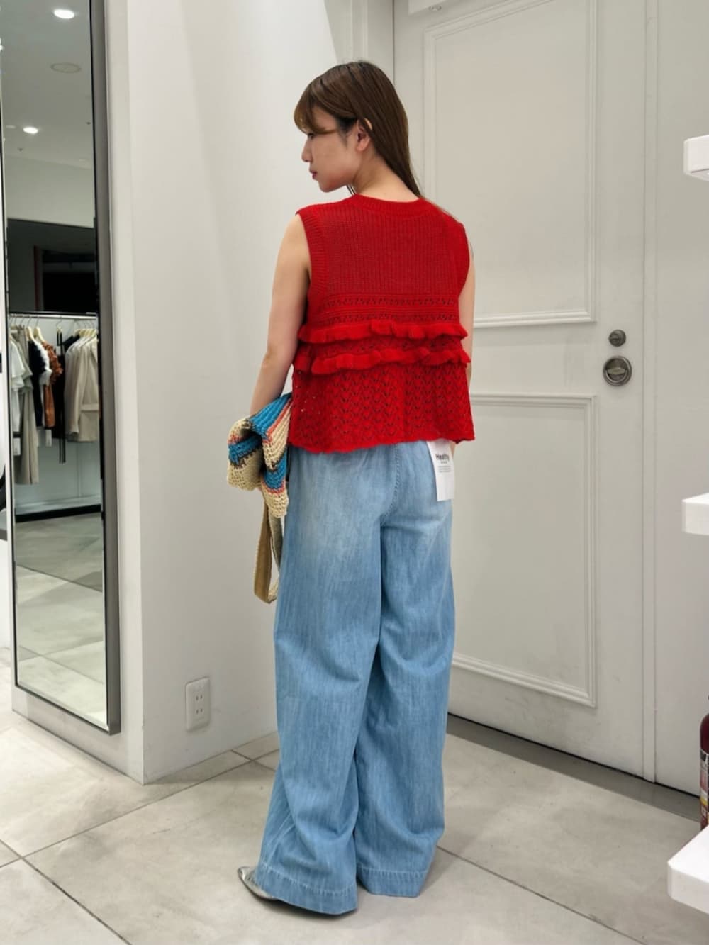 ブルー系のトートバッグ、レッド系のニット/セーター、ブルー系のデニムパンツを着用したレディースの春コーディネートの4枚目の写真