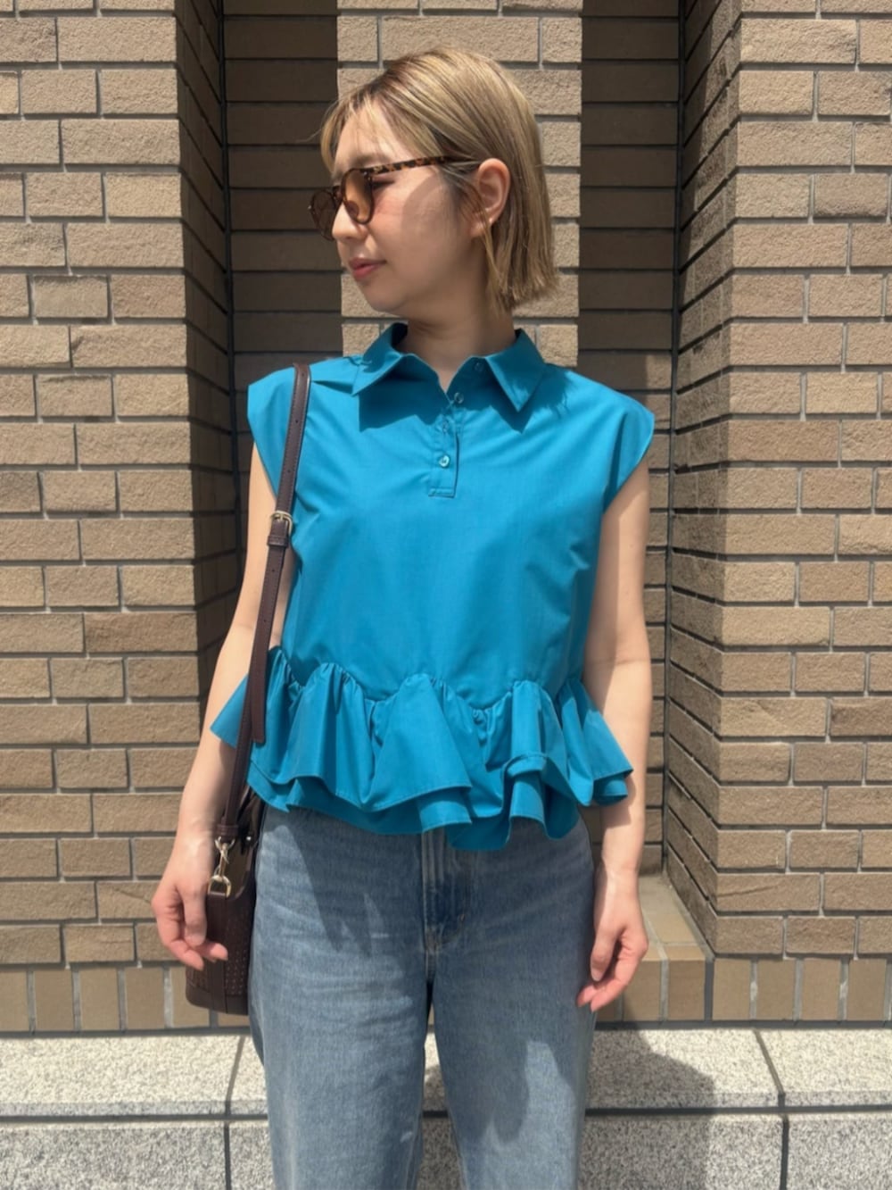 ブルー系のデニムパンツ、ブルー系のシャツ/ブラウス、オレンジ系のボストンバッグを着用したレディースの春コーディネートの5枚目の写真