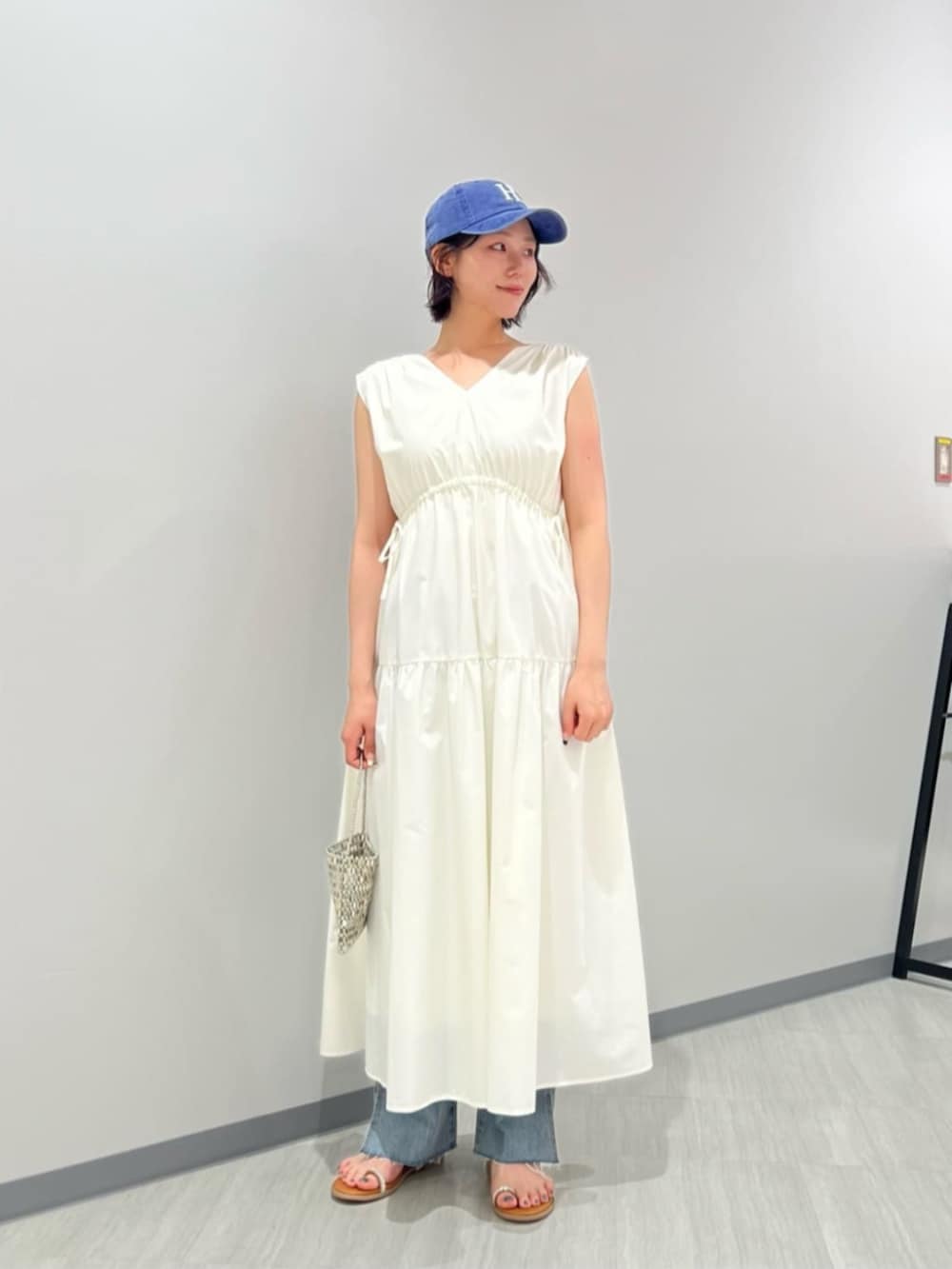 ブルー系のデニムパンツ、イエロー系のサンダル、ホワイト系のワンピースを着用したレディースの夏コーディネートの2枚目の写真