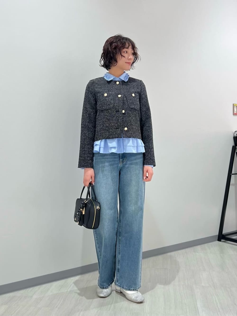 ブルー系のデニムパンツ、ブラック系のボストンバッグ、ブラック系のノーカラージャケットを着用したレディースの春コーディネートの2枚目の写真