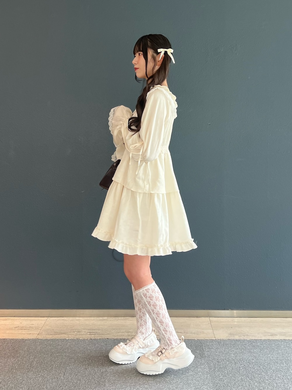 ピンク系のスニーカー、ホワイト系のワンピース、ブラウン系のハンドバッグを着用したレディースの夏コーディネートの3枚目の写真
