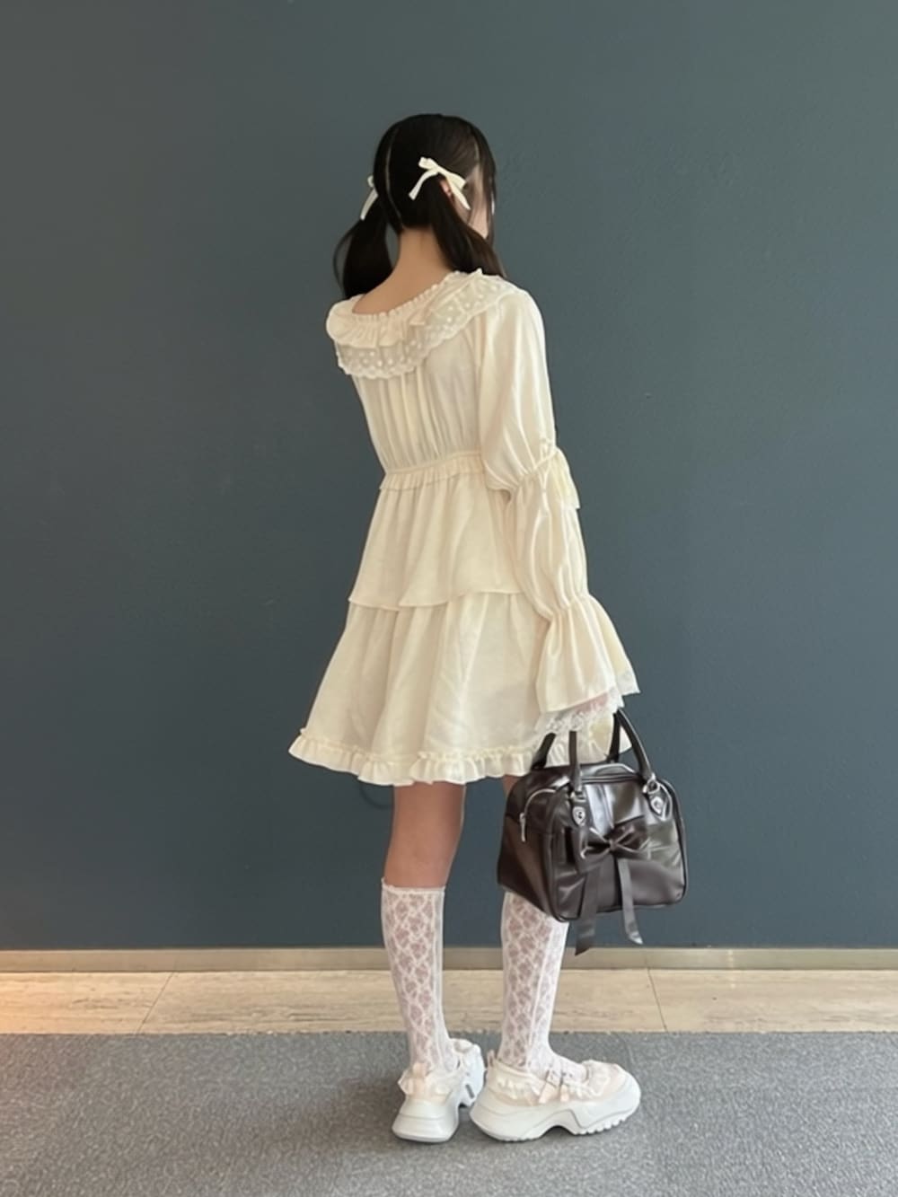 ピンク系のスニーカー、ホワイト系のワンピース、ブラウン系のハンドバッグを着用したレディースの夏コーディネートの5枚目の写真