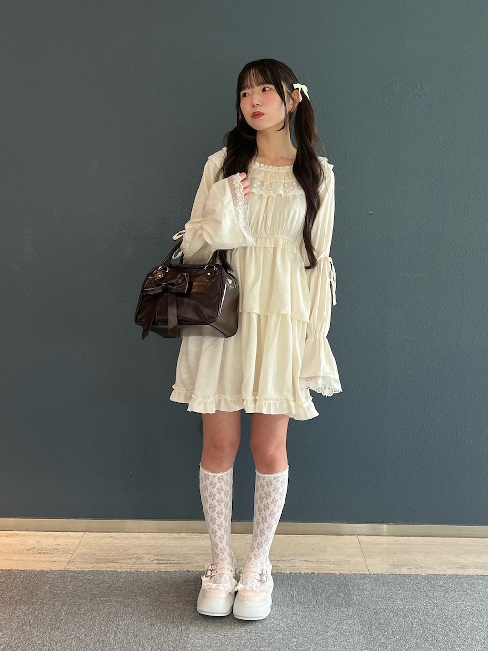 ピンク系のスニーカー、ホワイト系のワンピース、ブラウン系のハンドバッグを着用したレディースの夏コーディネートの2枚目の写真