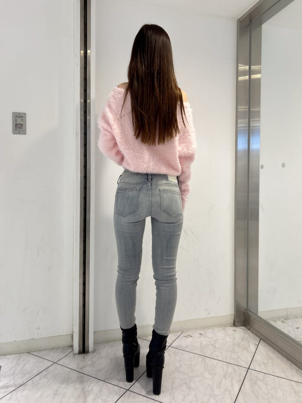 ブルー系のデニムパンツ、ピンク系のニット/セーター、ブラック系のブーツを着用したレディースの冬コーディネートの3枚目の写真