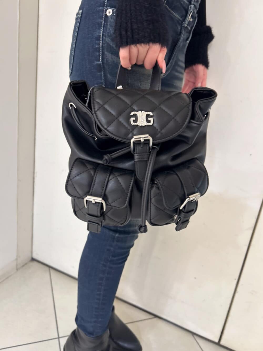 ブラック系のニット/セーター、ブラック系のバックパック/リュック、ブルー系のデニムパンツを着用したレディースの冬コーディネートの9枚目の写真