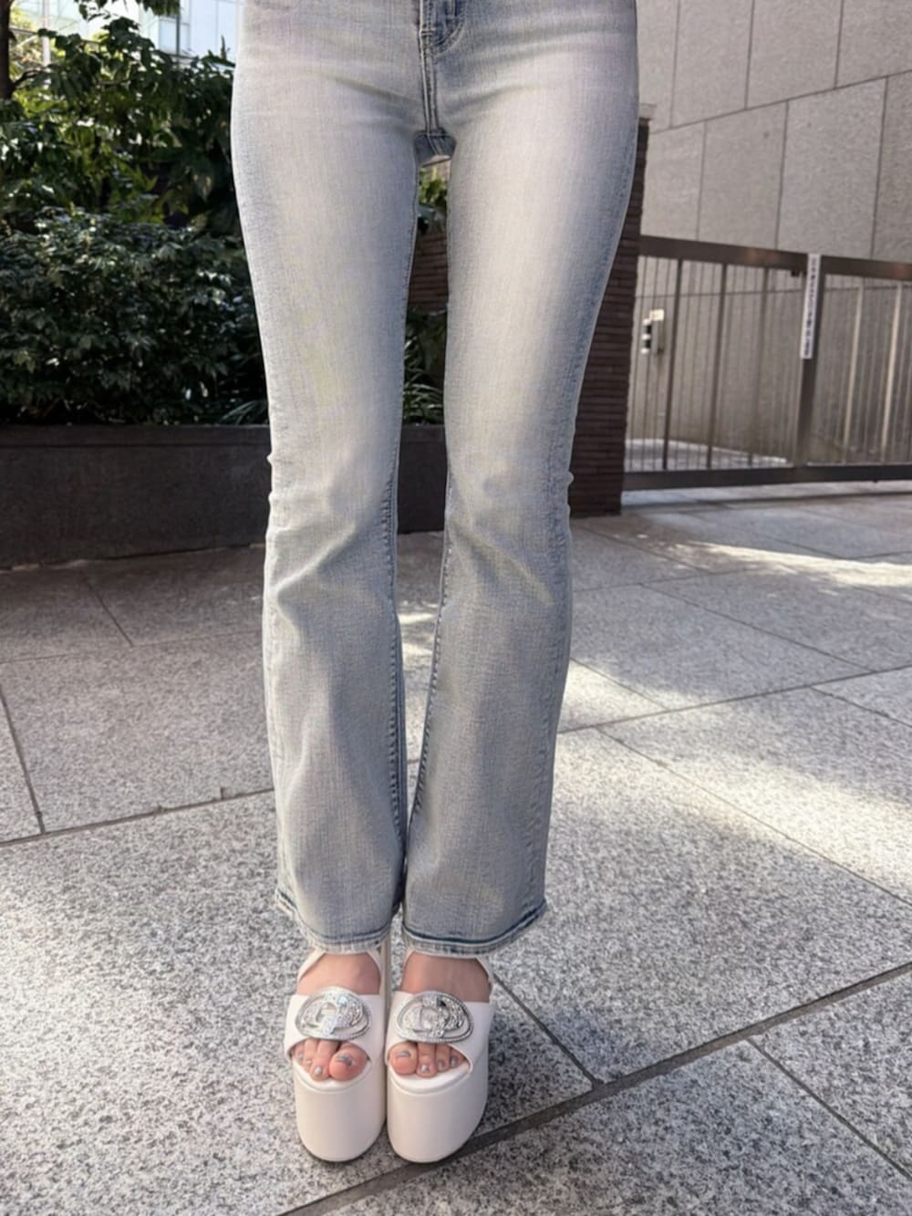 ブルー系のデニムパンツ、ホワイト系のサンダル、ホワイト系のハンドバッグを着用したレディースの春コーディネートの8枚目の写真