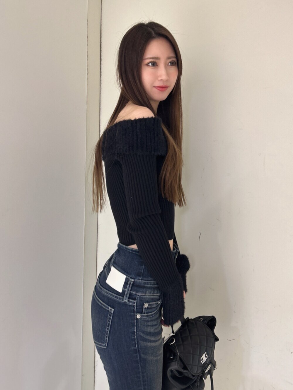 ブラック系のニット/セーター、ブラック系のバックパック/リュック、ブルー系のデニムパンツを着用したレディースの冬コーディネートの5枚目の写真