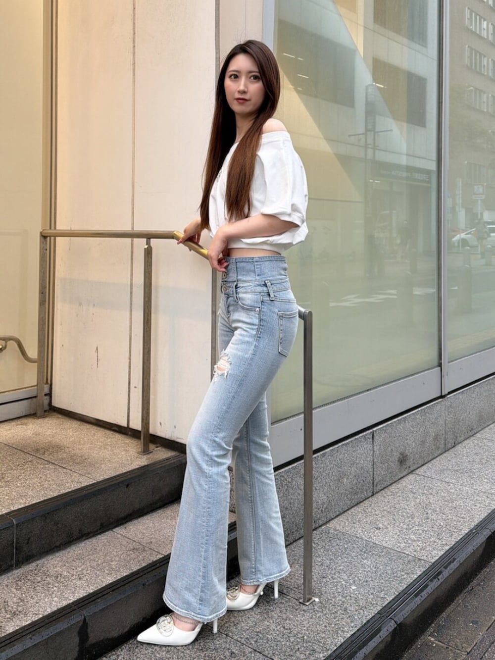 ブルー系のデニムパンツ、ホワイト系のパンプス、ホワイト系のTシャツ/カットソーを着用したレディースの春コーディネートの2枚目の写真