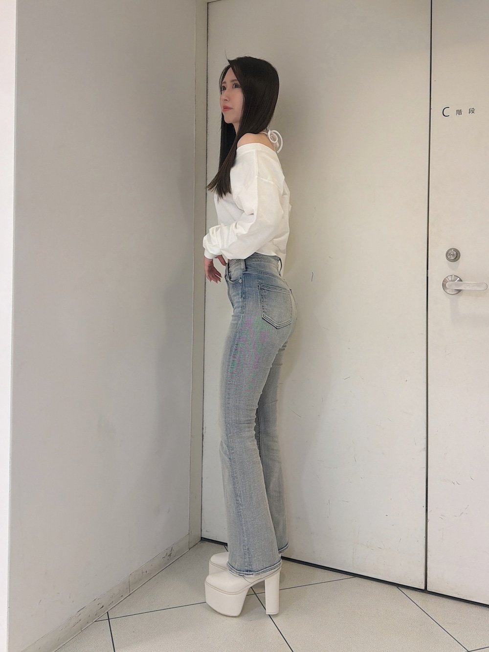 ホワイト系のスウェット、ブルー系のデニムパンツ、ホワイト系のブーツを着用したレディースの秋コーディネートの2枚目の写真