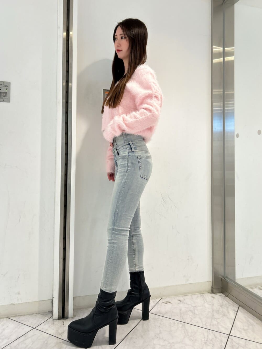 ブルー系のデニムパンツ、ピンク系のニット/セーター、ブラック系のブーツを着用したレディースの冬コーディネートの2枚目の写真