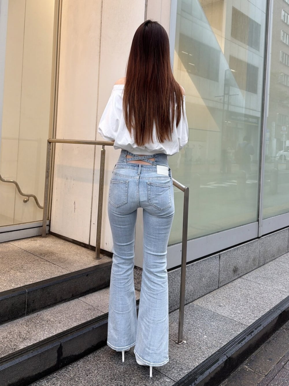 ブルー系のデニムパンツ、ホワイト系のパンプス、ホワイト系のTシャツ/カットソーを着用したレディースの春コーディネートの3枚目の写真