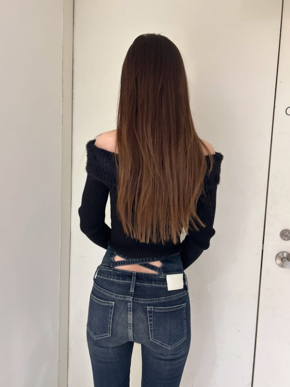 ブラック系のニット/セーター、ブラック系のバックパック/リュック、ブルー系のデニムパンツを着用したレディースの冬コーディネートの6枚目の写真