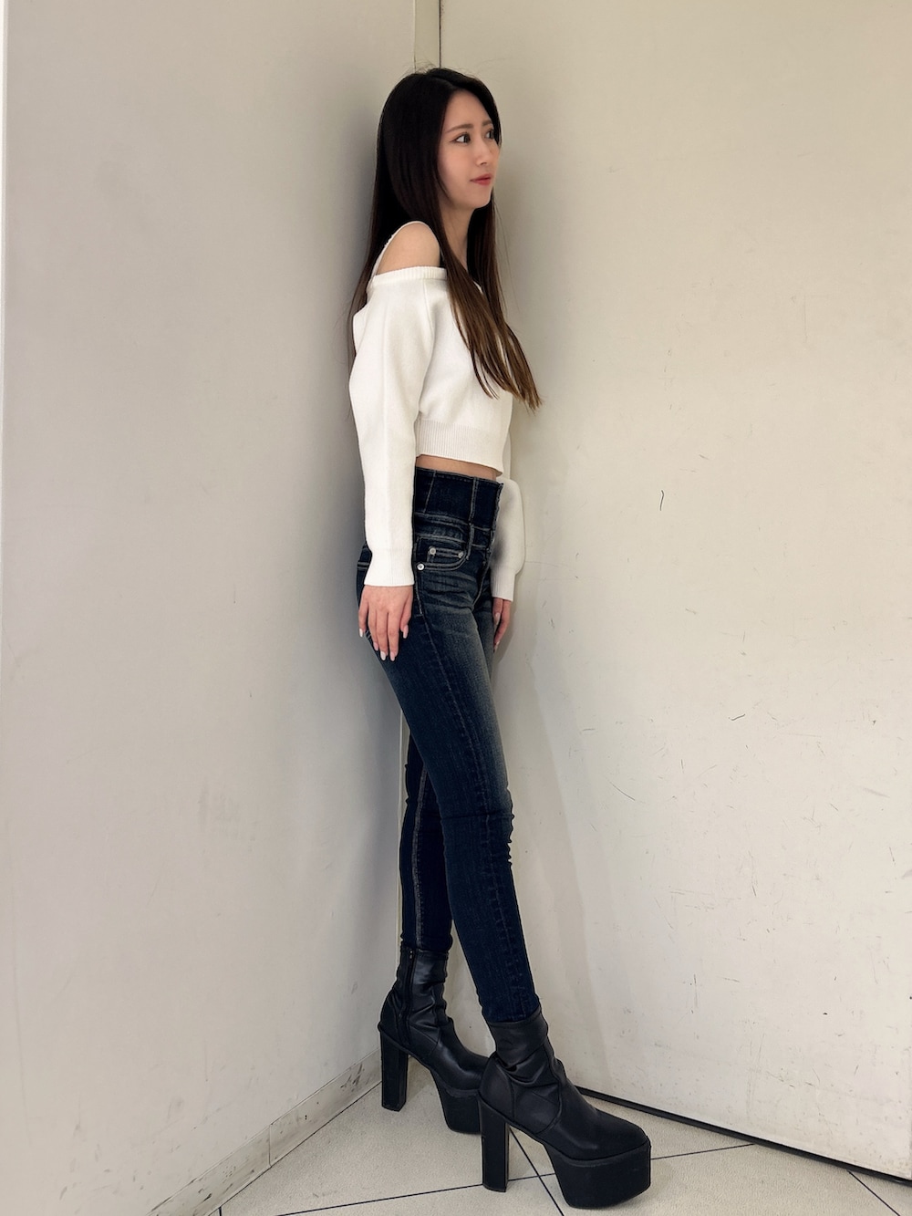 ホワイト系のニット/セーター、ブルー系のデニムパンツ、ブラック系のブーツを着用したレディースの冬コーディネートの2枚目の写真