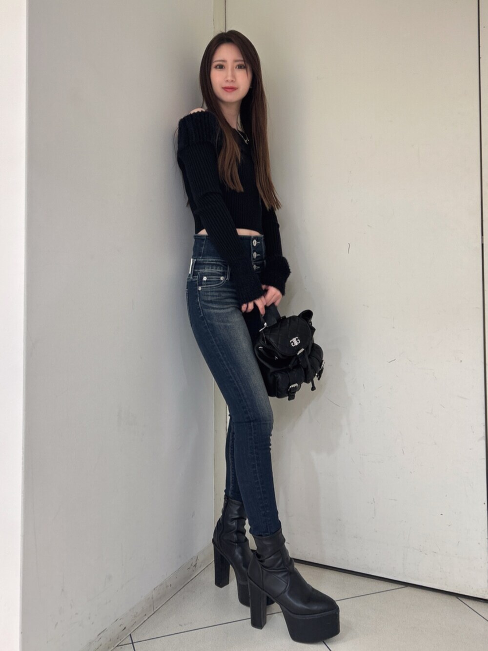 ブラック系のニット/セーター、ブラック系のバックパック/リュック、ブルー系のデニムパンツを着用したレディースの冬コーディネートの2枚目の写真