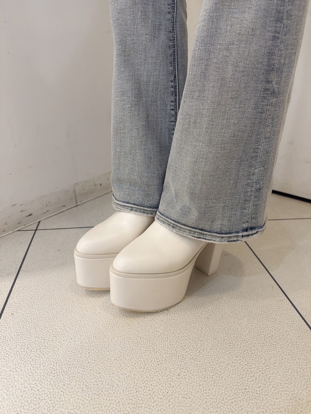 ホワイト系のスウェット、ブルー系のデニムパンツ、ホワイト系のブーツを着用したレディースの秋コーディネートの9枚目の写真