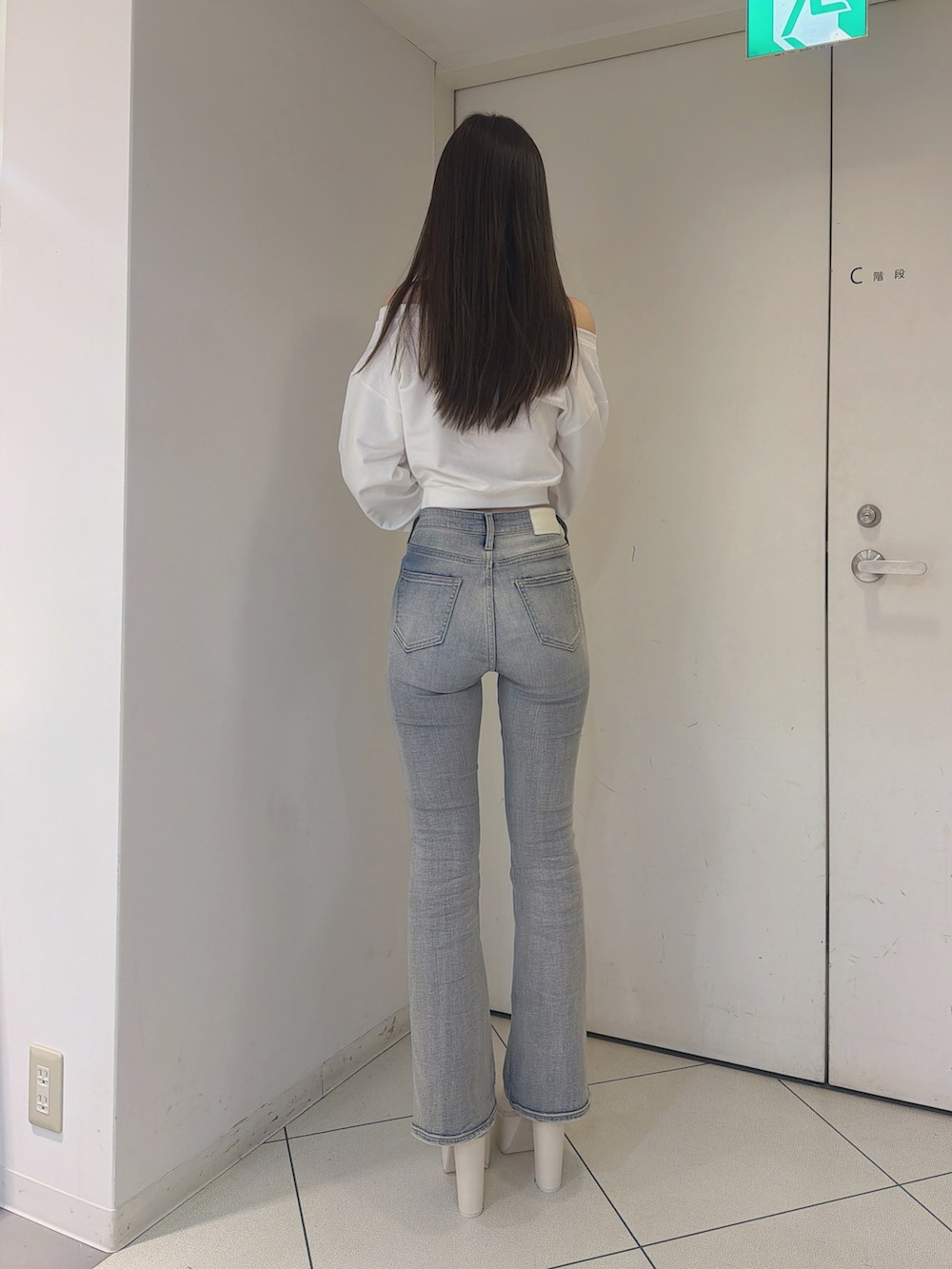 ホワイト系のスウェット、ブルー系のデニムパンツ、ホワイト系のブーツを着用したレディースの秋コーディネートの3枚目の写真