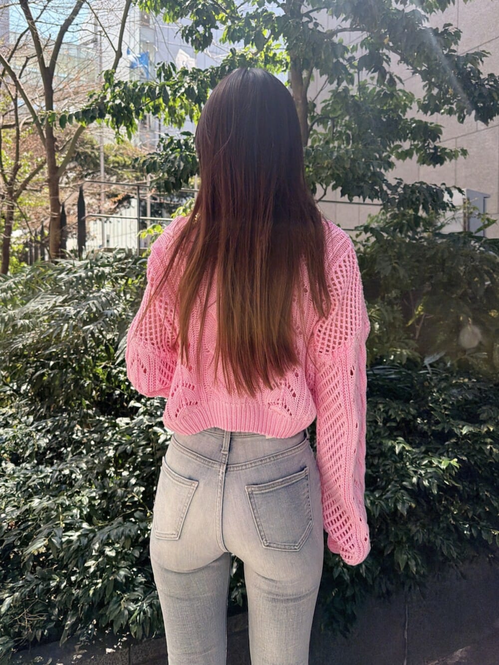 ブルー系のデニムパンツ、ホワイト系のサンダル、ピンク系のニット/セーターを着用したレディースの春コーディネートの6枚目の写真