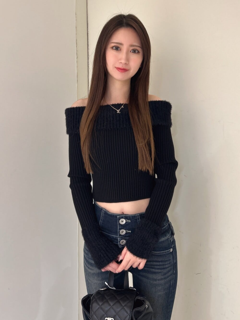 ブラック系のニット/セーター、ブラック系のバックパック/リュック、ブルー系のデニムパンツを着用したレディースの冬コーディネートの4枚目の写真