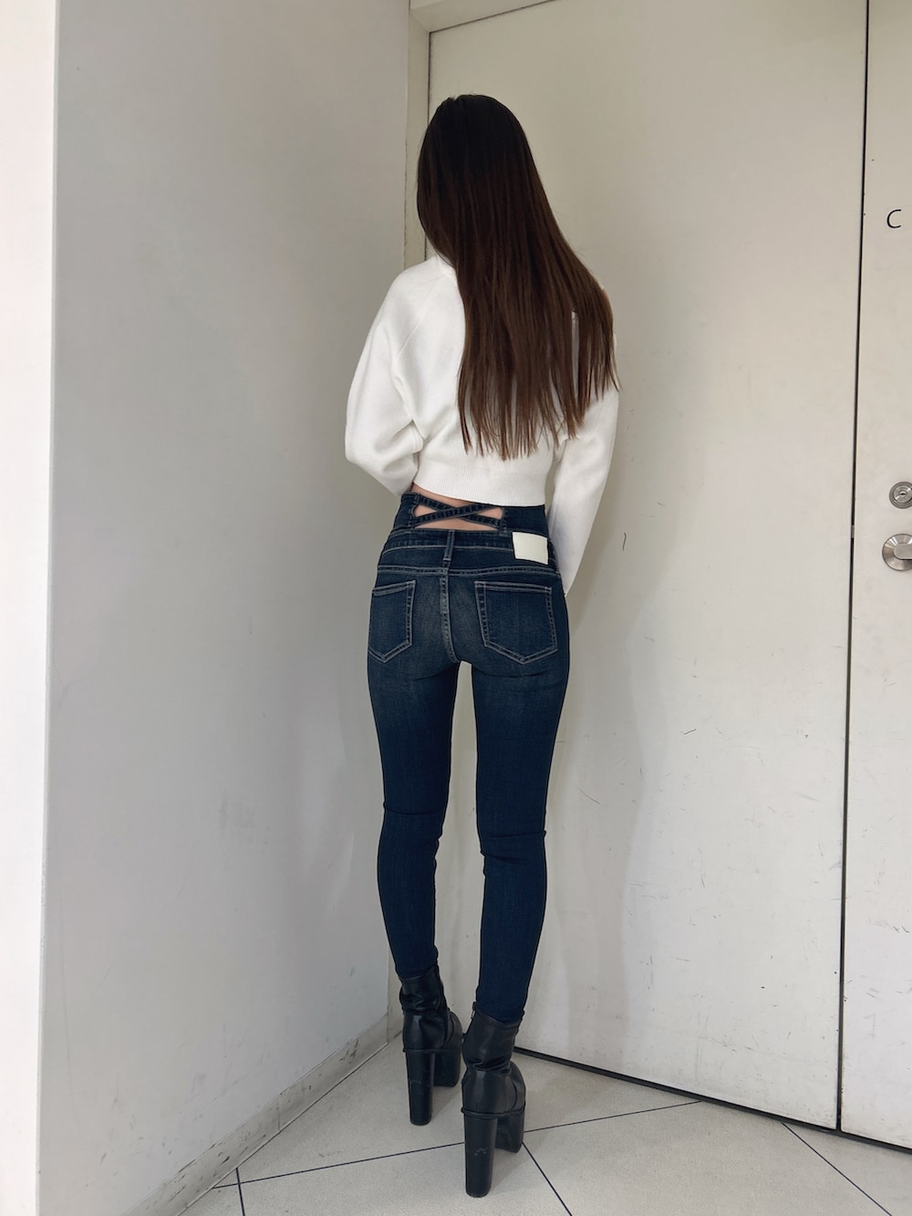 ホワイト系のニット/セーター、ブルー系のデニムパンツ、ブラック系のブーツを着用したレディースの冬コーディネートの3枚目の写真