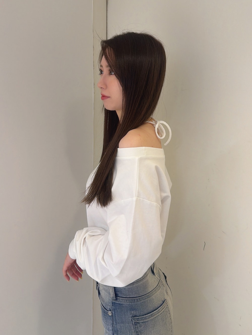 ホワイト系のスウェット、ブルー系のデニムパンツ、ホワイト系のブーツを着用したレディースの秋コーディネートの5枚目の写真