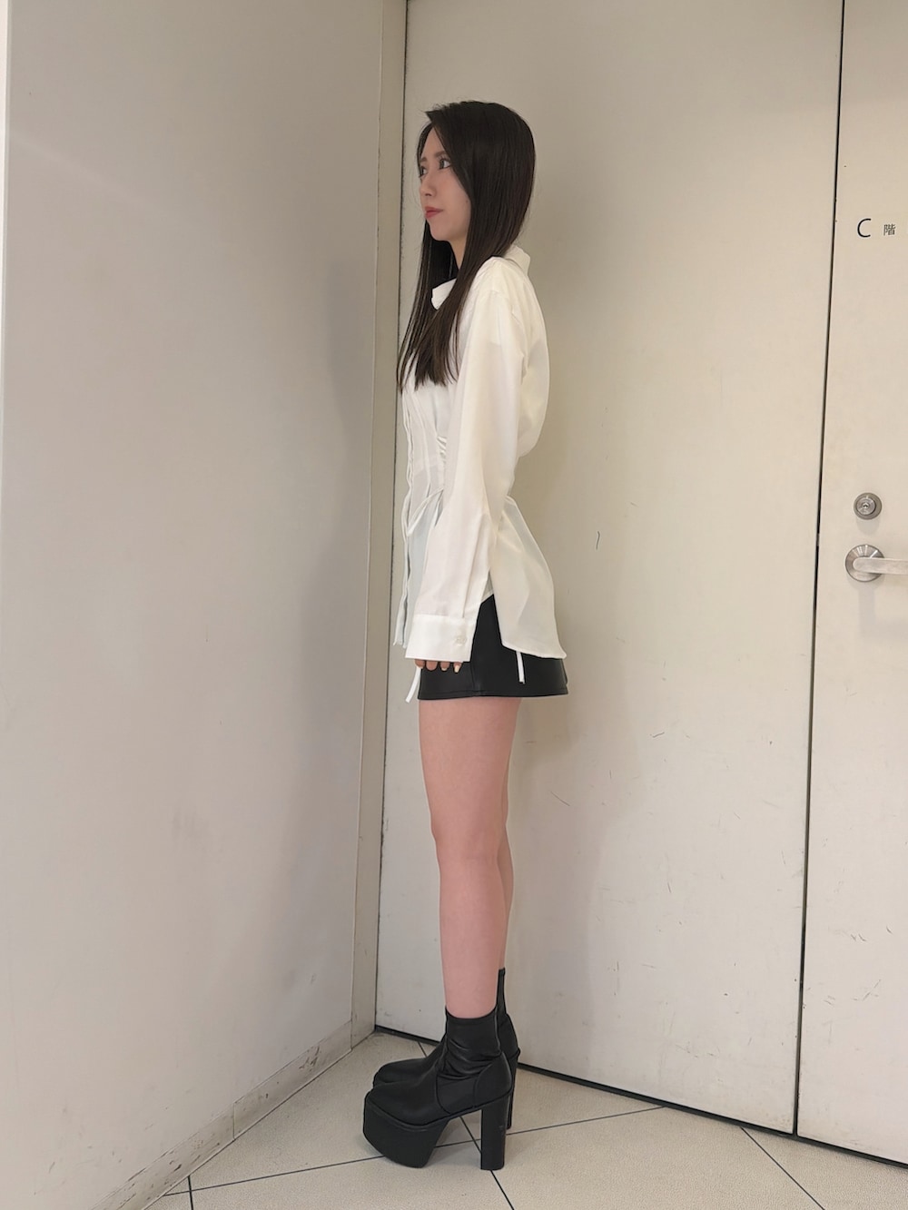 ホワイト系のシャツ/ブラウス、ブラック系のスカート、ブラック系のブーツを着用したレディースの秋コーディネートの2枚目の写真