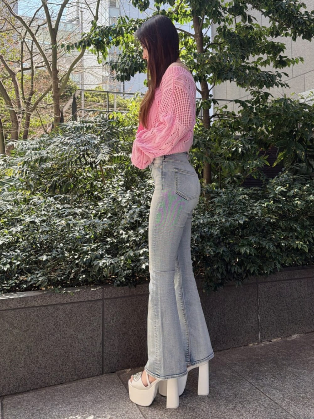 ブルー系のデニムパンツ、ホワイト系のサンダル、ピンク系のニット/セーターを着用したレディースの春コーディネートの2枚目の写真