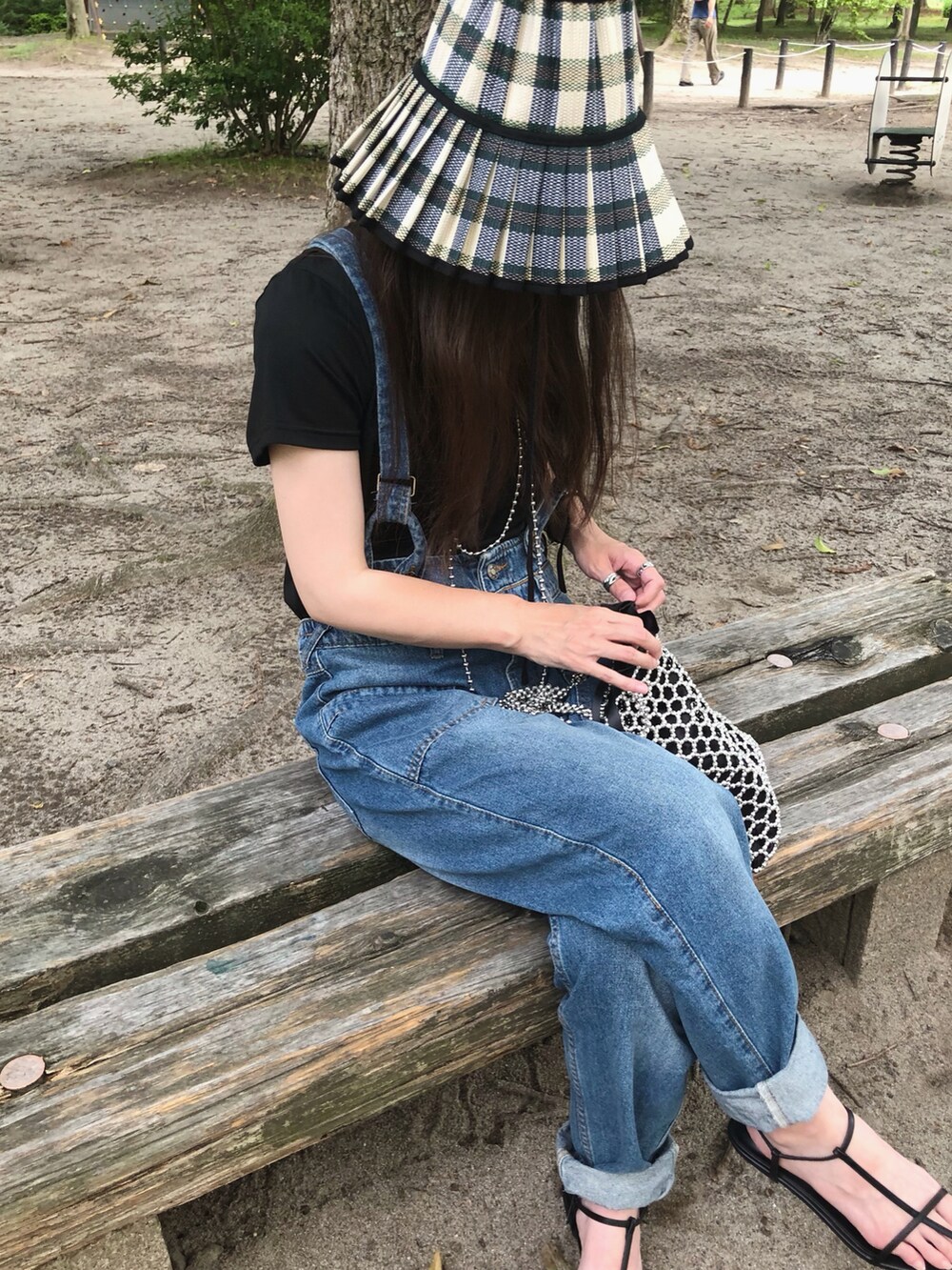 シルバー系のハンドバッグ、ブルー系のデニムパンツ、ブラック系のサンダルを着用したレディースの夏コーディネートの2枚目の写真