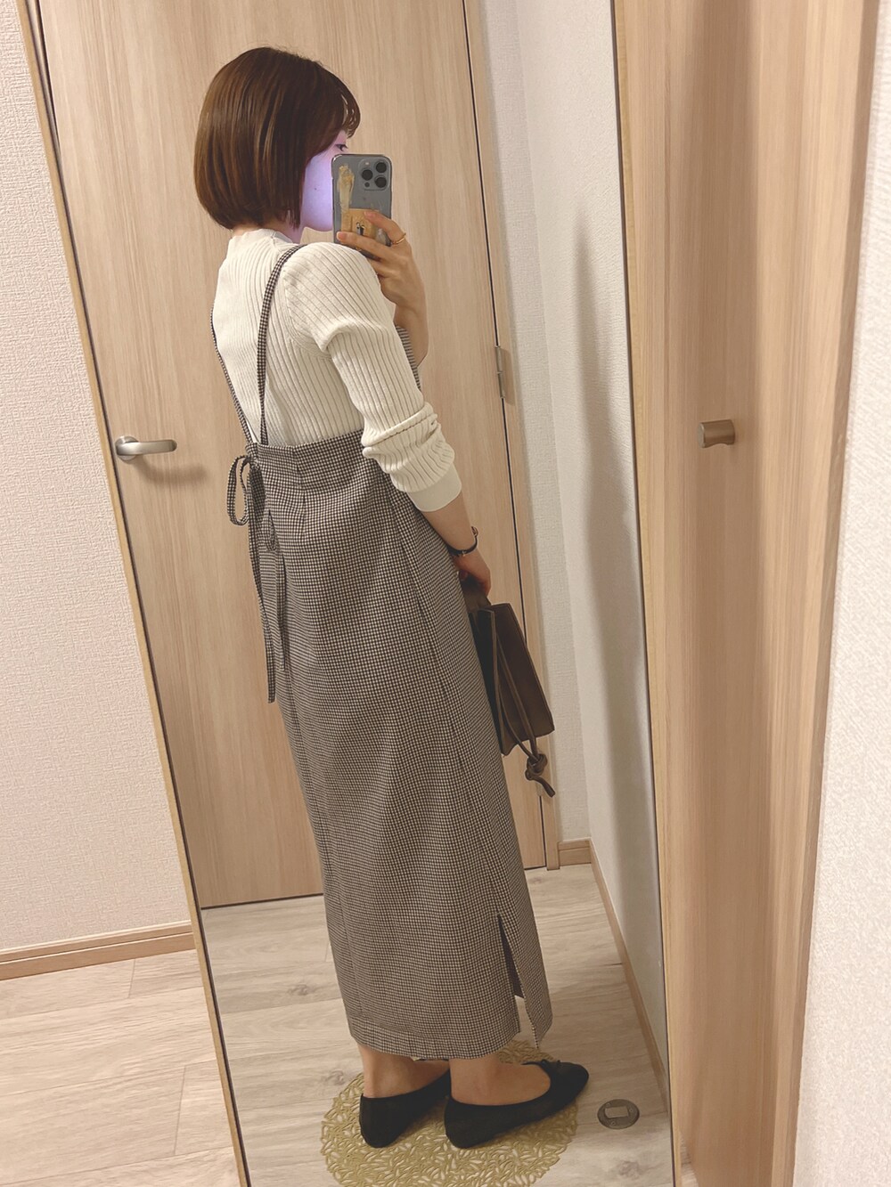 ブラック系のバレエシューズ、ブラウン系のジャンパースカート、ブラウン系のショルダーバッグを着用したレディースの春コーディネートの2枚目の写真