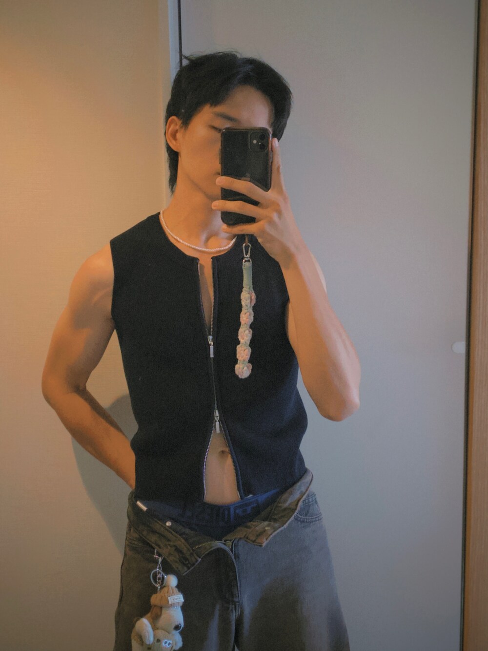 ブラウン系のデニムパンツ、ブラック系のタンクトップ、ブルー系のキャップを着用したメンズの秋コーディネートの2枚目の写真