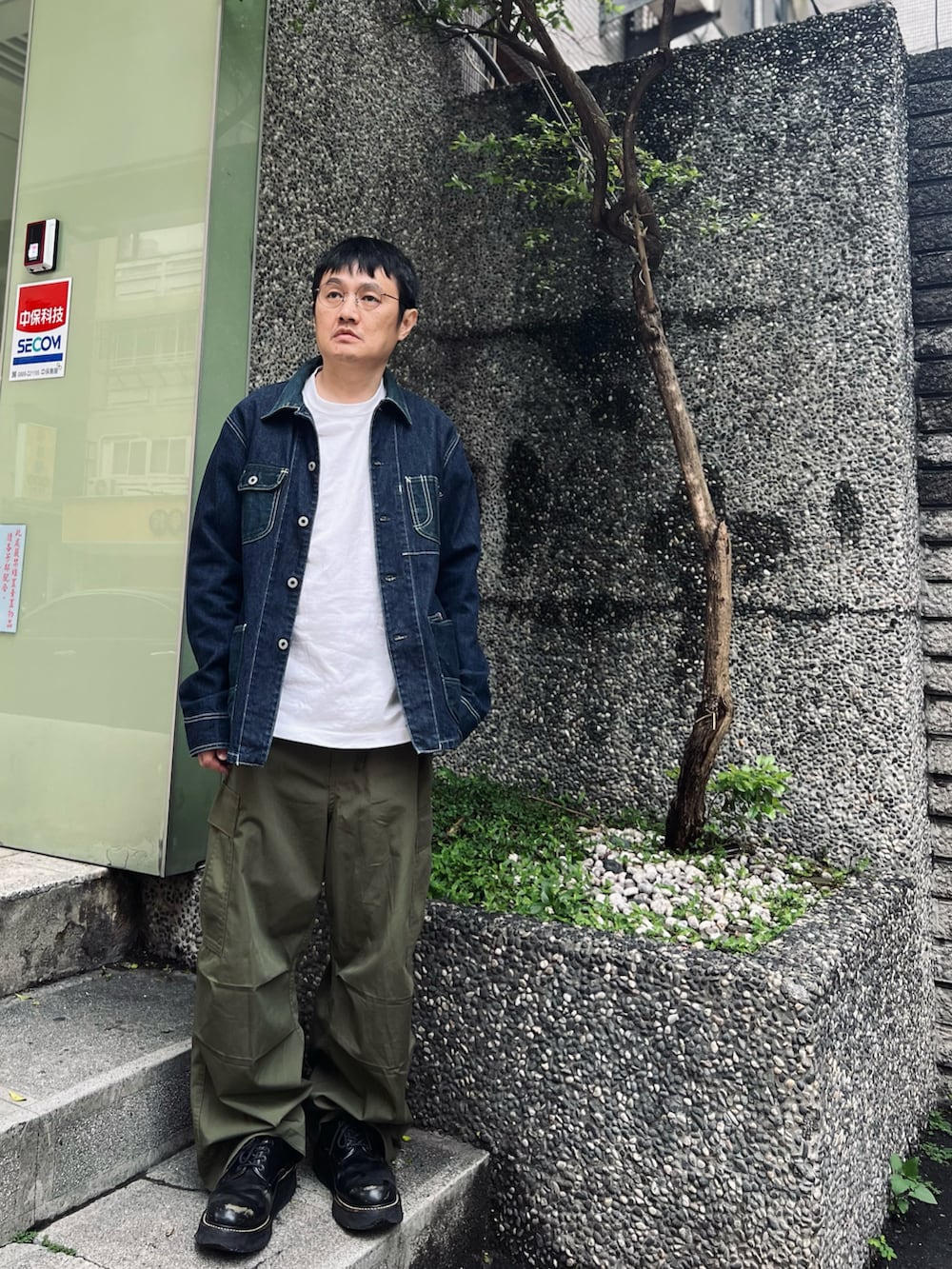 ブルー系のデニムジャケット、グリーン系のパンツ、ブラック系のシューズを着用したメンズの春コーディネートの2枚目の写真