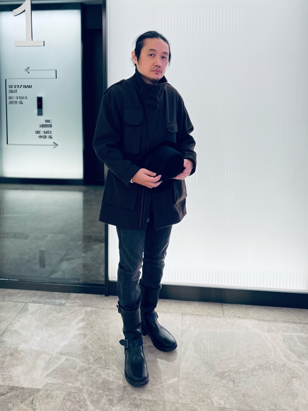 ブラック系のTシャツ/カットソー、ブラウン系のノーカラーコート、ブラック系のブーツを着用したメンズの冬コーディネートの3枚目の写真