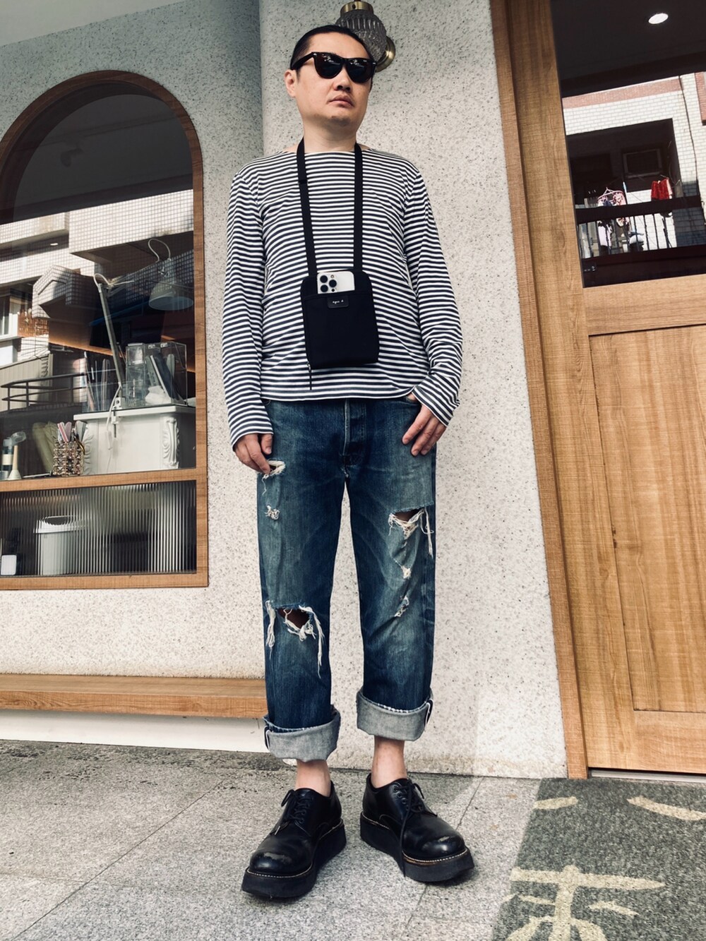 ブラック系のショルダーバッグ、ブルー系のTシャツ/カットソー、ブルー系のデニムパンツを着用したメンズの夏コーディネートの2枚目の写真