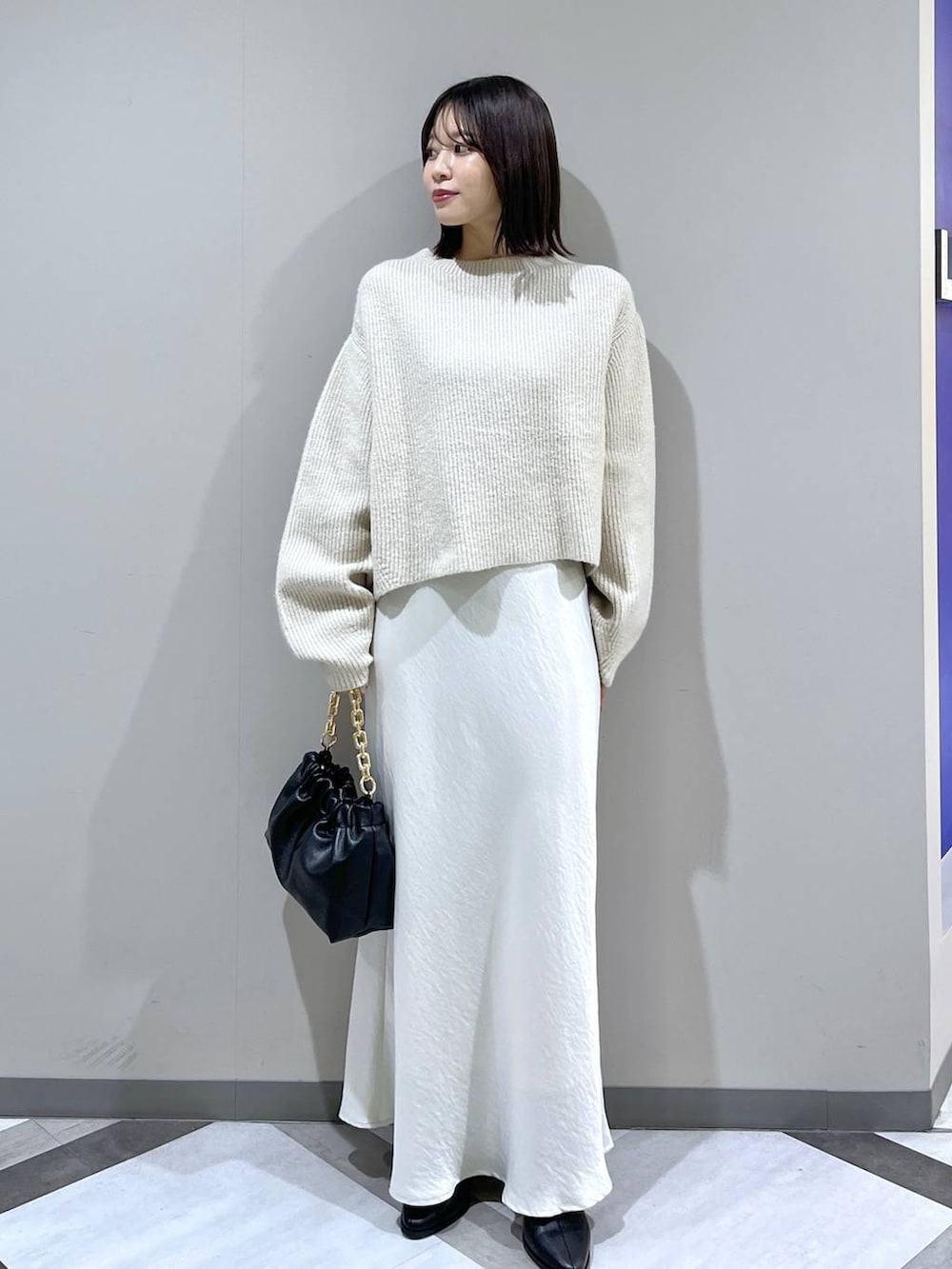 ホワイト系のニット/セーター、ホワイト系のスカート、ブラック系のショルダーバッグを着用したレディースの冬コーディネートの4枚目の写真