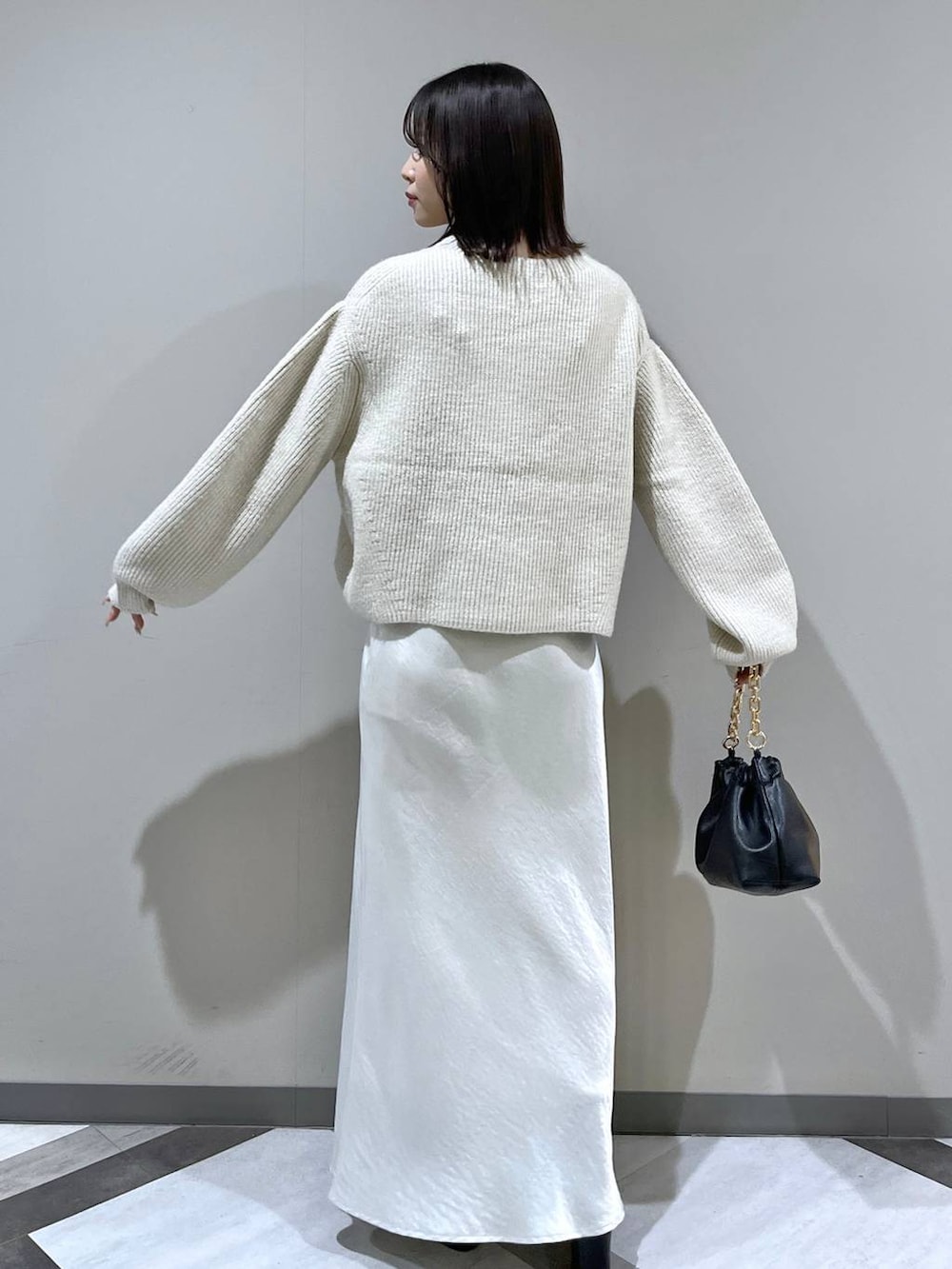 ホワイト系のニット/セーター、ホワイト系のスカート、ブラック系のショルダーバッグを着用したレディースの冬コーディネートの6枚目の写真