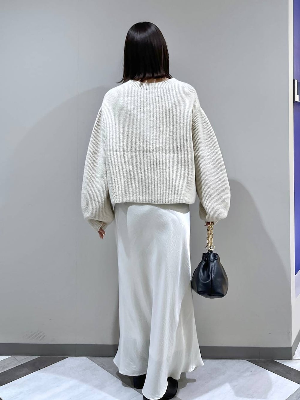 ホワイト系のニット/セーター、ホワイト系のスカート、ブラック系のショルダーバッグを着用したレディースの冬コーディネートの3枚目の写真