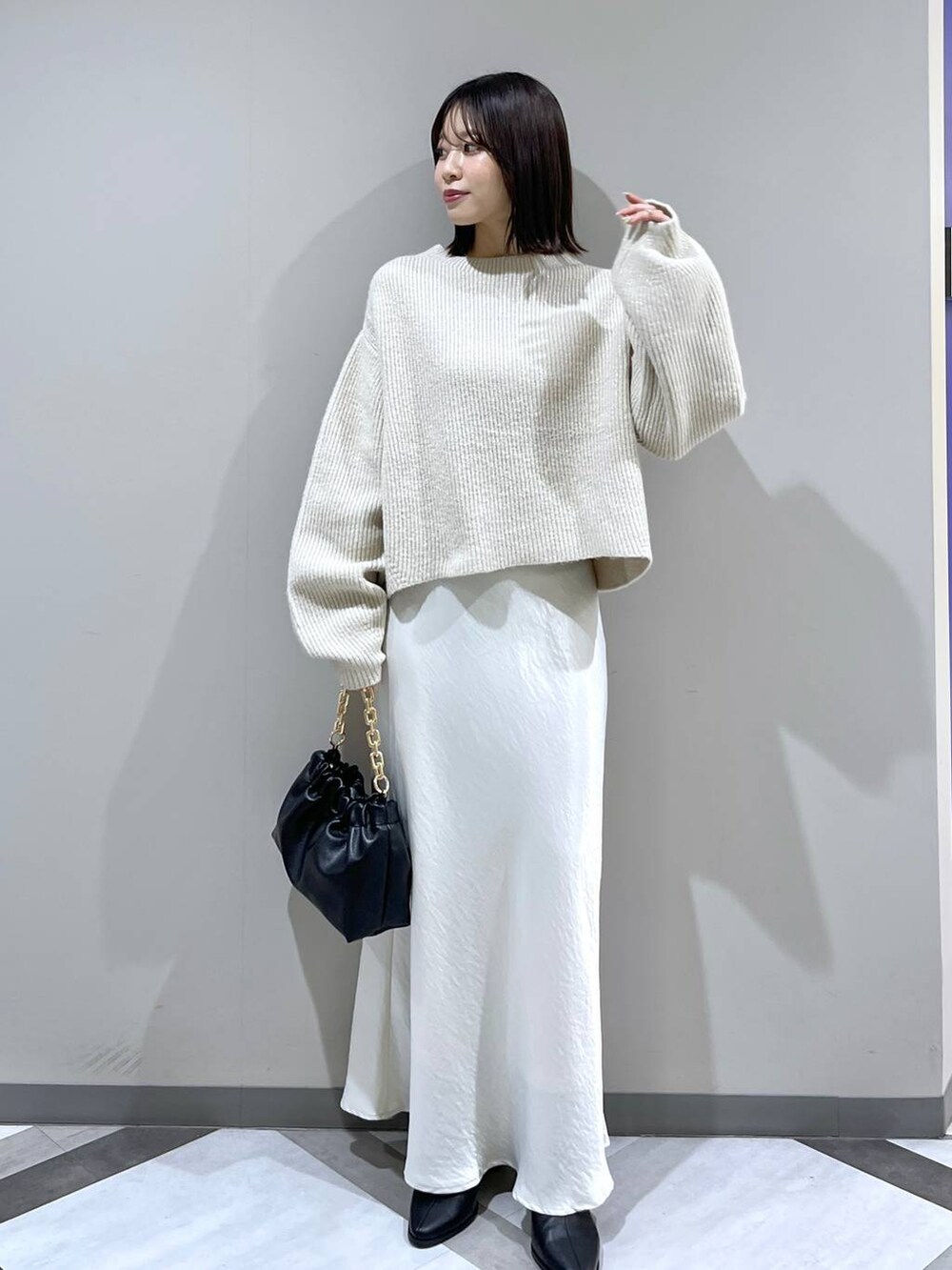 ホワイト系のニット/セーター、ホワイト系のスカート、ブラック系のショルダーバッグを着用したレディースの冬コーディネートの5枚目の写真