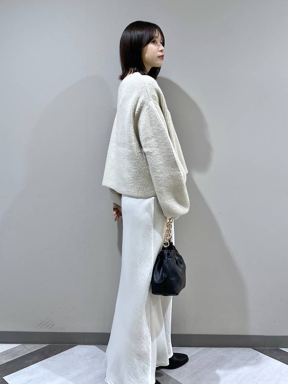 ホワイト系のニット/セーター、ホワイト系のスカート、ブラック系のショルダーバッグを着用したレディースの冬コーディネートの2枚目の写真