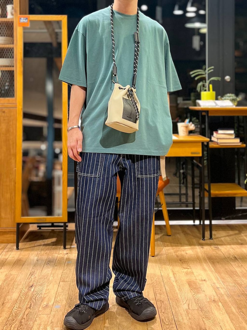 グレー系のショルダーバッグ、グリーン系のTシャツ/カットソー、ブラック系のサンダルを着用したメンズの夏コーディネートの3枚目の写真