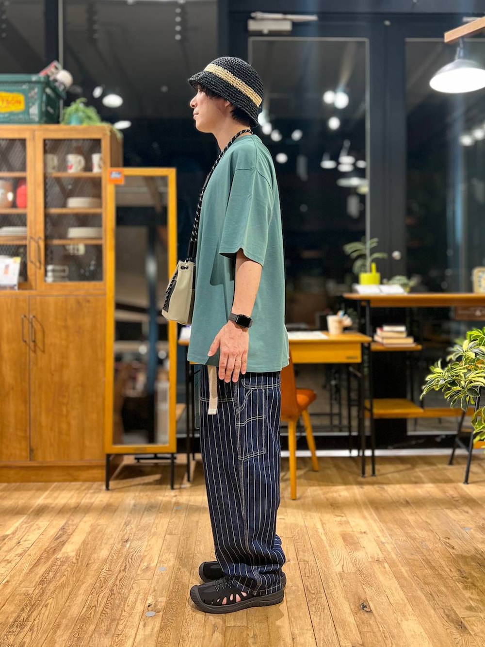 グレー系のショルダーバッグ、グリーン系のTシャツ/カットソー、ブラック系のサンダルを着用したメンズの夏コーディネートの4枚目の写真