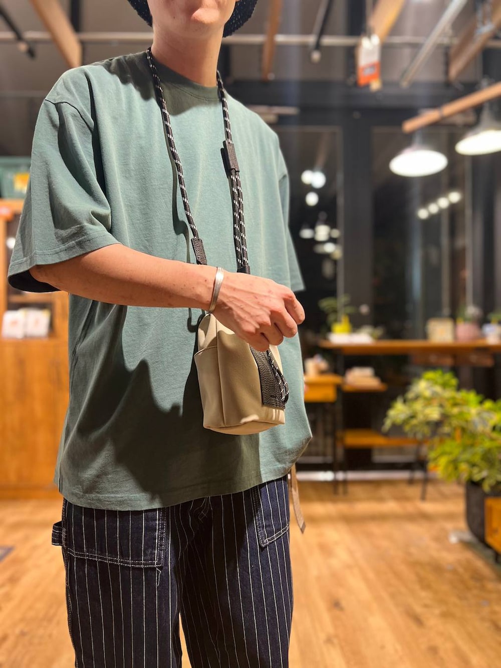グレー系のショルダーバッグ、グリーン系のTシャツ/カットソー、ブラック系のサンダルを着用したメンズの夏コーディネートの7枚目の写真