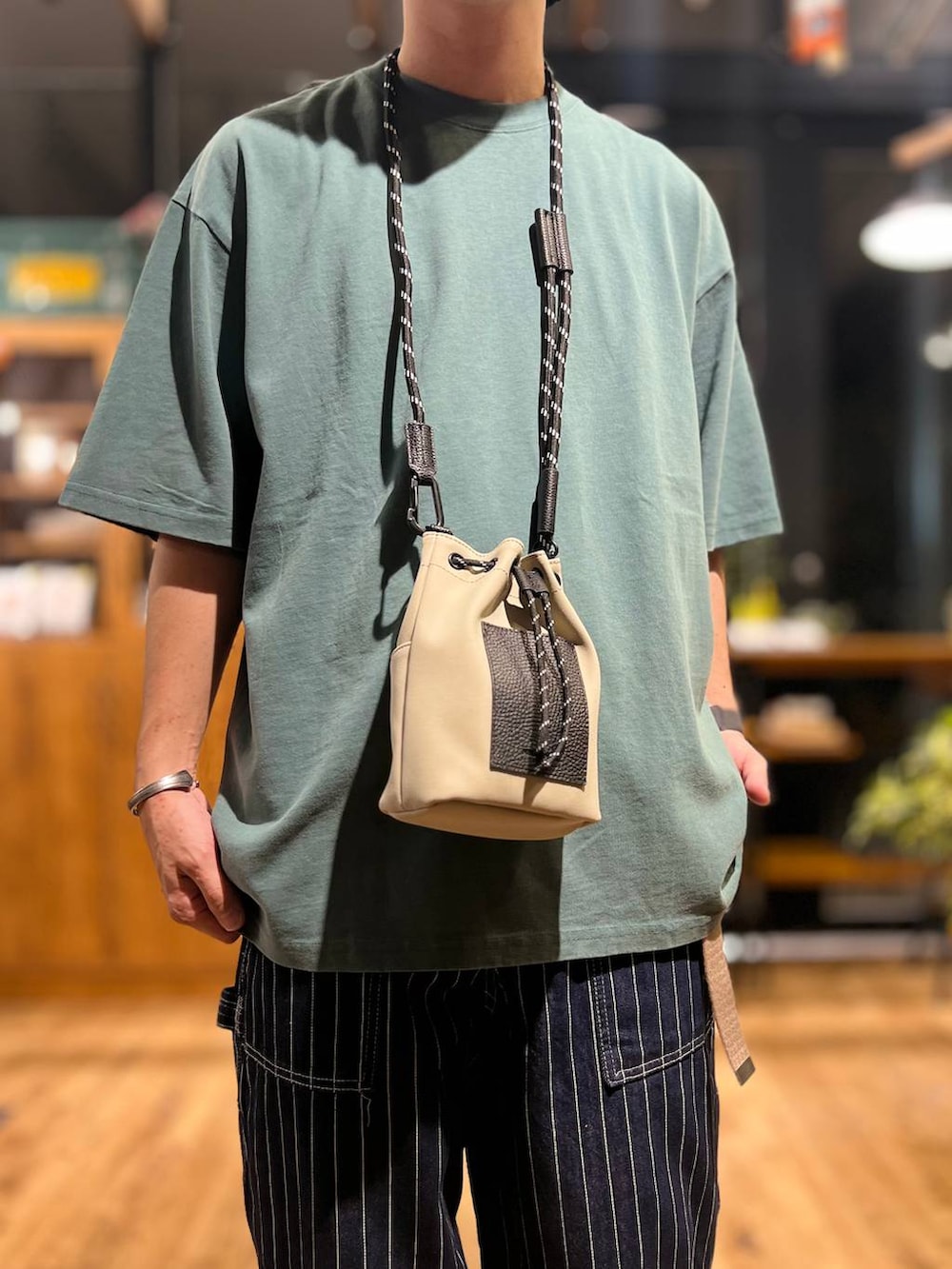 グレー系のショルダーバッグ、グリーン系のTシャツ/カットソー、ブラック系のサンダルを着用したメンズの夏コーディネートの6枚目の写真