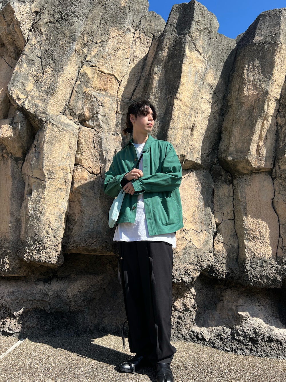 グリーン系のその他アウター、ホワイト系のバッグ、ブラック系のスラックスを着用したメンズの春コーディネートの2枚目の写真