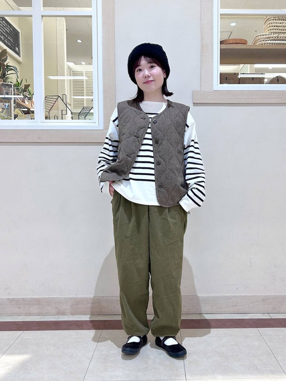 ベージュ系のベスト、グリーン系のその他パンツ、ブラウン系のスニーカーを着用したレディースの冬コーディネートの4枚目の写真