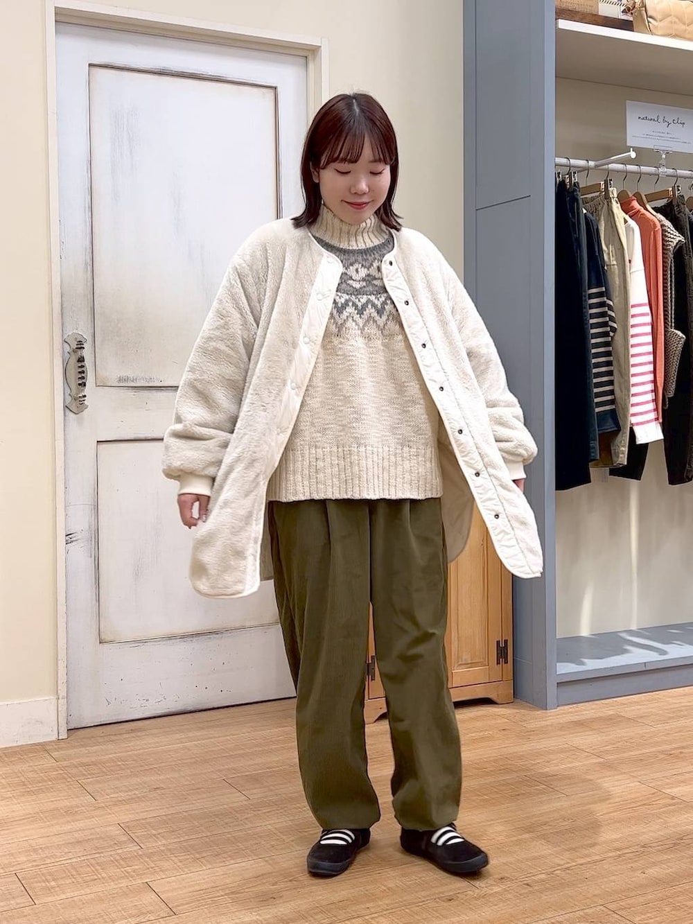 ホワイト系のノーカラーコート、グリーン系のその他パンツ、ブラウン系のスニーカーを着用したレディースの冬コーディネートの5枚目の写真