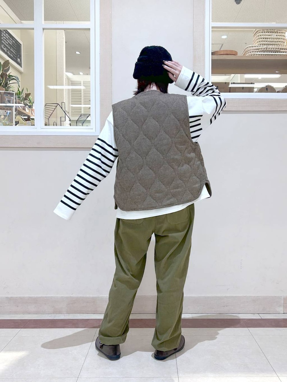 ベージュ系のベスト、グリーン系のその他パンツ、ブラウン系のスニーカーを着用したレディースの冬コーディネートの3枚目の写真